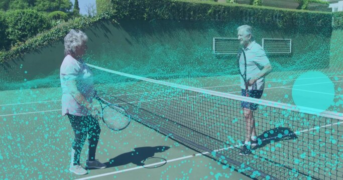 Standing senior couple in sportswear holding rackets by tennis net on court, preparing rally - Powered by Adobe