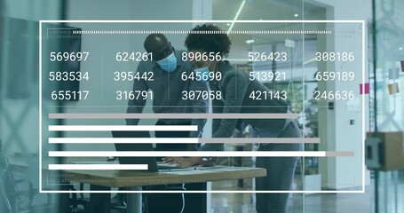 Reviewing laptop data at conference table, colleagues wearing surgical face masks with data overlay
