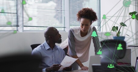 Reviewing senior colleagues in business attire analyzing chart data at office desk, with laptop