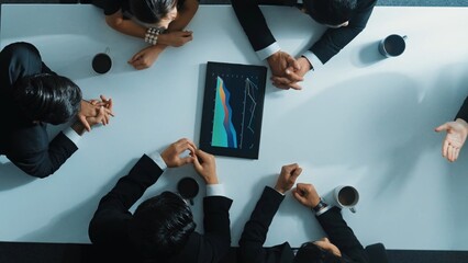 Top down aerial view of group of business people looking at financial chart while analyze and explain growing stock market statistic. Team placed tablet with chart at meeting table. Directorate.