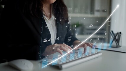 A business professional types on a keyboard with financial graphs and data overlays. This modern...