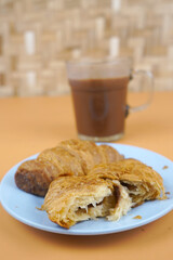 Croissants and hot cocoa on an orange background for breakfast or a snack.