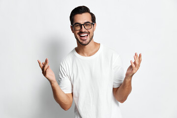 Fototapeta premium Full body cheerful smiling man in white t-shirt looking at camera with excitement and open hands, isolated on plain light background. People lifestyle concept.