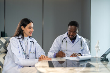 Diverse medical team african male doctor and female doctor collaborating and reviewing medical...