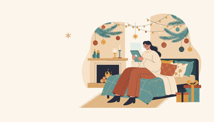 Woman uses tablet in a festive cozy bedroom by the fireplace Winter holiday relaxation and technology