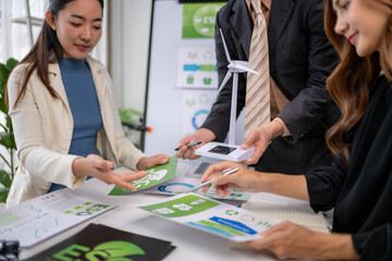 Business people discussing esg data, holding wind turbine model © Apichat