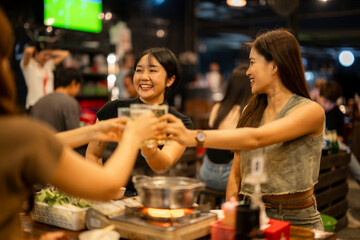 Asian friends toasting drinks celebrating dinner in restaurant