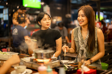 Happy asian women friends eating hot pot at night