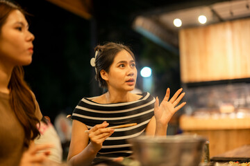 Asian women friends having a conversation in a restaurant at night