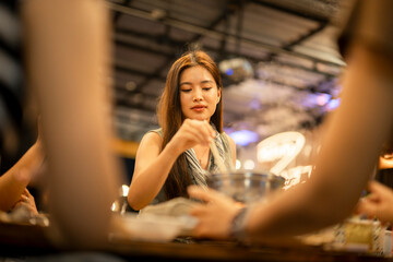 Asian woman enjoying hot pot dinner with friends