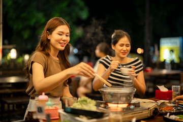 Asian friends enjoying hot pot dinner at night