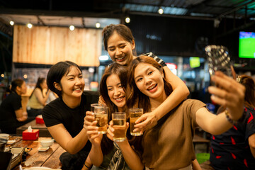 Asian women friends taking selfie cheering beer