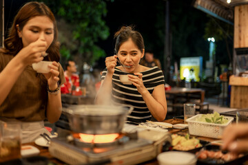 Asian women friends enjoying hot pot dinner at night