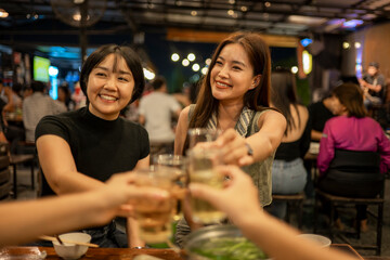 Asian women friends toasting drinks at restaurant