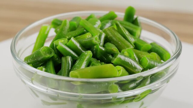 Fried wok green beans with onions and spices in a white plate on a gray background. Flat lay. Top view.