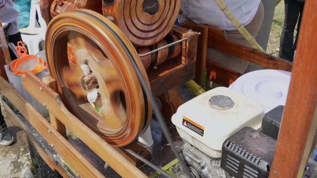 Close-up of a vibrant, rustic sugar cane juicing machine in action. Dynamic motion with spinning wheels and gears, capturing the essence of traditional agriculture on a sunny day.