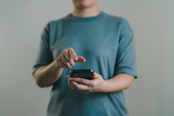 Tapping on smartphone in blue t-shirt. Reflects online activity, personal communication, digital...