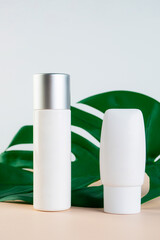 Cosmetic product in tube, bottle, lotion or serum with stylish props on light brown background. 