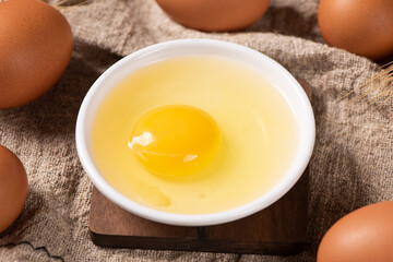 Broken raw egg with yolk on wooden table.