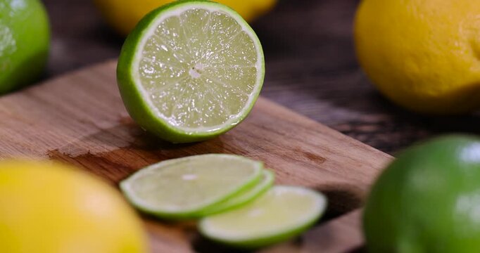 sliced juicy sour lime lying on the table with yellow lemons , sliced ripe citrus fruits lime and large lemons are lying on a wooden table