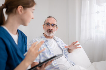 Obraz premium Female nurse assisting an elderly patient in bed while reviewing medical information
