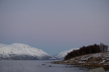 Twilight over snowy fjord and winter shoreline in Arctic Tromsø, Norway