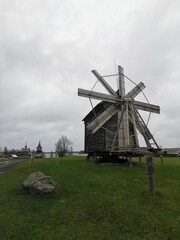 Fototapeta premium Historic wooden windmill at Kizhi Open-Air Museum, Karelia, Russia. A symbol of traditional Russian architecture and history, set against a cloudy northern landscape