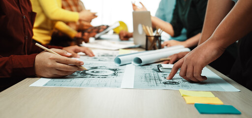 A dynamic team meeting in a modern office where professionals engage with architectural blueprints, emphasizing collaboration and creative planning among diverse team members. SACTR