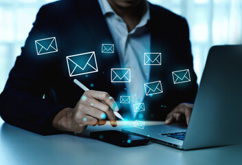 A man is writing on a laptop with a pen and a cell phone