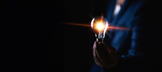 A man is holding a light bulb in his hand. Concept of innovation and creativity, as the light bulb...
