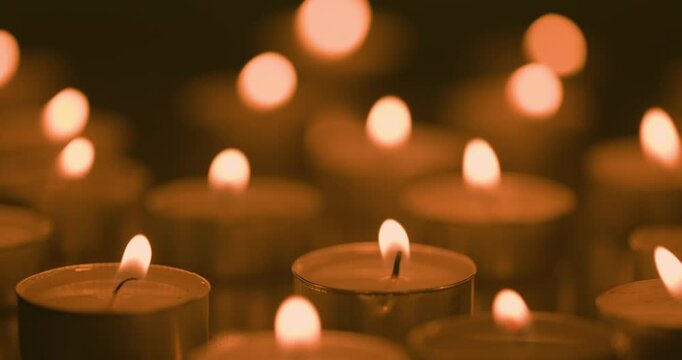 burning candles with defocused lights on black background