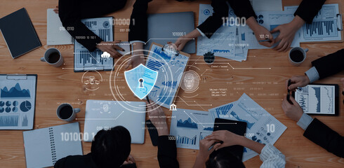 A top-down view of a business meeting focused on data security and digital analysis, showcasing professionals collaborating on charts and graphs while surrounded by technology and coffee. Trope