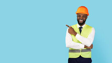 Check This. Black Male Construction Engineer Pointing Finger Aside At Copy Space Over Blue Studio Background, Smiling Black Builder Man Demonstrating Free Place For Advertisement, Panorama