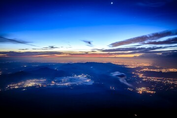 Fototapeta premium Twilight Over Mountain Silhouettes with City Lights and Celestial Glow