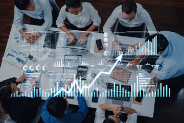 A top-down view of a business team engaged in collaborative work, analyzing financial trends and developing strategies in a modern office setting, showcasing teamwork and innovation. Scalp