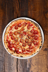 Overhead angle of a pepperoni pizza on a wood table 
