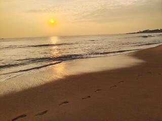 Footprints on calm beach at sunrise 