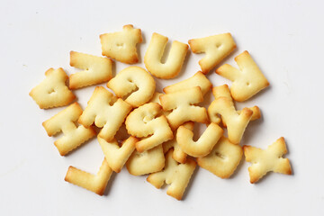 A pile of alphabet-shaped butter cookies arranged on a white background.