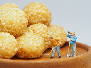 Mini toy of action figure and traditional snack from Indonesia at table with blurred background. Miniature and Food photography concept design. Minifigure people character with Onde Onde Wijen.