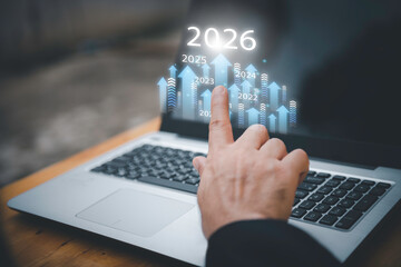 Businessman drawing digital growth arrows and bar graph with 2026 target. Futuristic concept for business goals, technology strategy, data-driven planning, success and innovation.