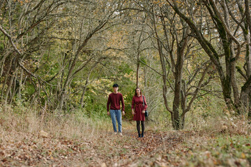 A candid, authentic portrait of a couple walking hand in hand along a quiet autumn woodland path,...