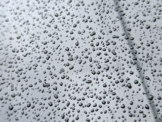 Texture of countless small, dark water droplets scattered densely across a smooth, reflective, light gray or silver surface, likely metal or glass.