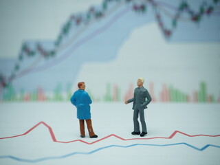 Fototapeta premium Mini toy of action figure at outdoor with blurred background. Toy photography concept design. Minifigure of businessman character with market graph. 