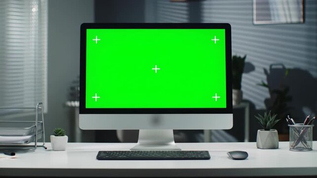 Green screen computer on office desk, sunlit window blinds, showcasing presentations or content