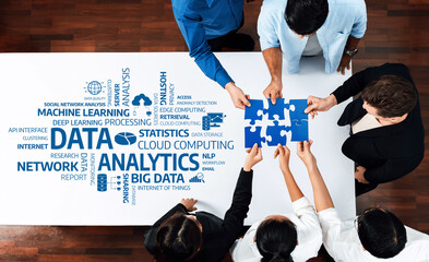 Professionals engage in a collaborative effort around a table, aligning puzzle pieces that symbolize the integration of analytics and data in modern business strategies. Amity