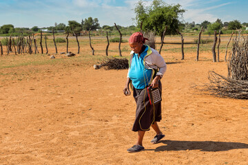 village old african woman using a solar panel with radio, to recharge phones and light, donated by a charity NGO, to improve life in rural areas