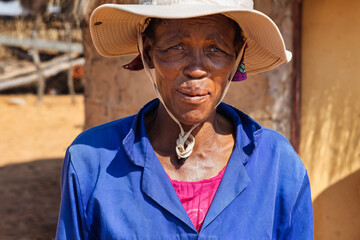 close up portrait old african woman, village life, standing in front of the mud house