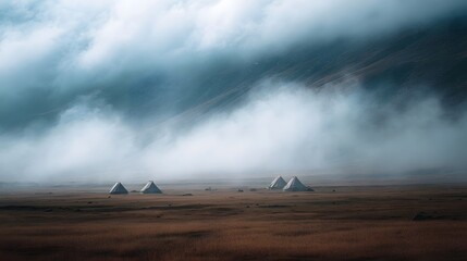 An ethereal and misty landscape unfolds with several white nomadic tents set against a backdrop of rolling hills and a golden fog covered plain