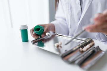 Woman pharmacist Working and Arranging Medications
counting and arrange pills on stainless counting tray with spatula in pharmacy.