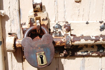 Rusty old padlocked and bolted door with peeling paint on timber door and frame